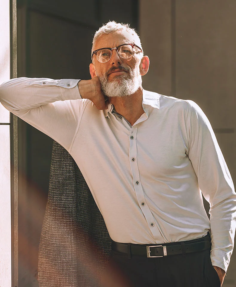 Close-up shot of a man with a beard and glasses, wearing a collared dress shirt. The focus is on his facial features, emphasizing the beard and mustache, with the background indicating an indoor setting. - Hemorrhoidectomy in Coral Gables, FL